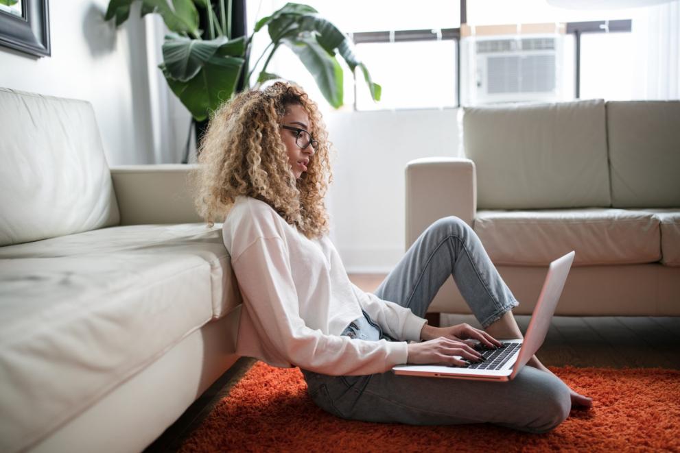 girl sitting on a carpet typing a computer