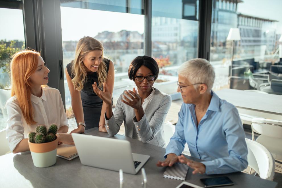 © Adobe Stock 4 women of various ages and countries in front of a laptop discussing