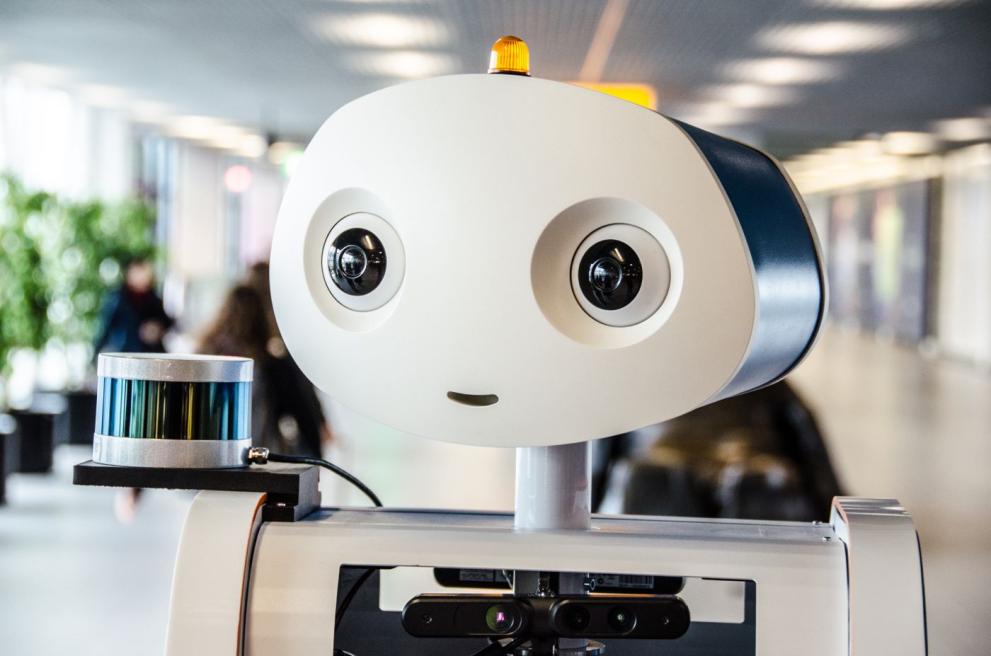 A humanoid robot sits behind a desk. 