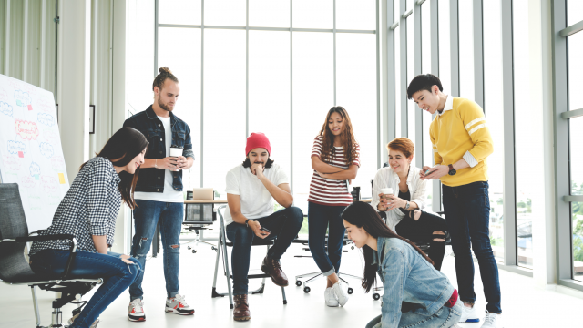 Young creative diverse group meeting and looking at project plan lay out on floor discuss or brainstorm business strategy with post note. Workshop for startup team in modern office. Happy workplace.