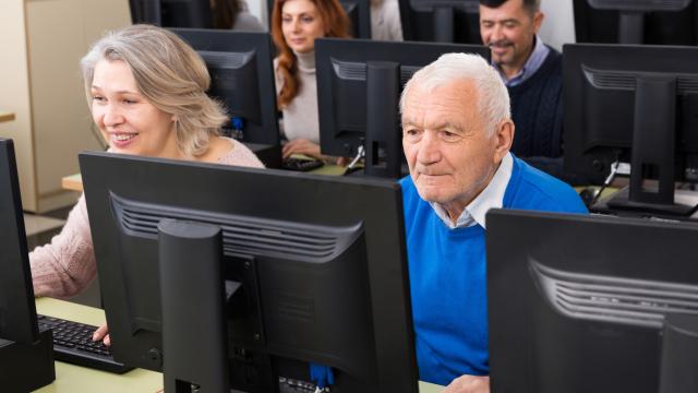 Photo of several elderly people behind computer screens smiling at the screens