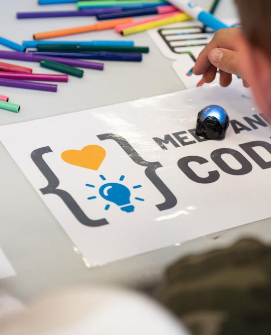  a child colouring the logo of the Meet and code project