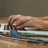 Hands on computer next to a stethoscope