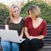 Two women sitting next to each other in front of a laptop