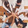 A photo of a group of 5 people on a desk, holding hands | Nomadicdisplays.eu