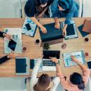 Top view of businessman executive in group meeting with other businessmen and businesswomen in modern office with laptop computer, coffee and documents
