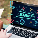 Hands holding a laptop with the words "Learning" written on it